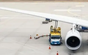 Ground crew refueling private jet wing with sustainable aviation fuel at Singapore airport tarmac