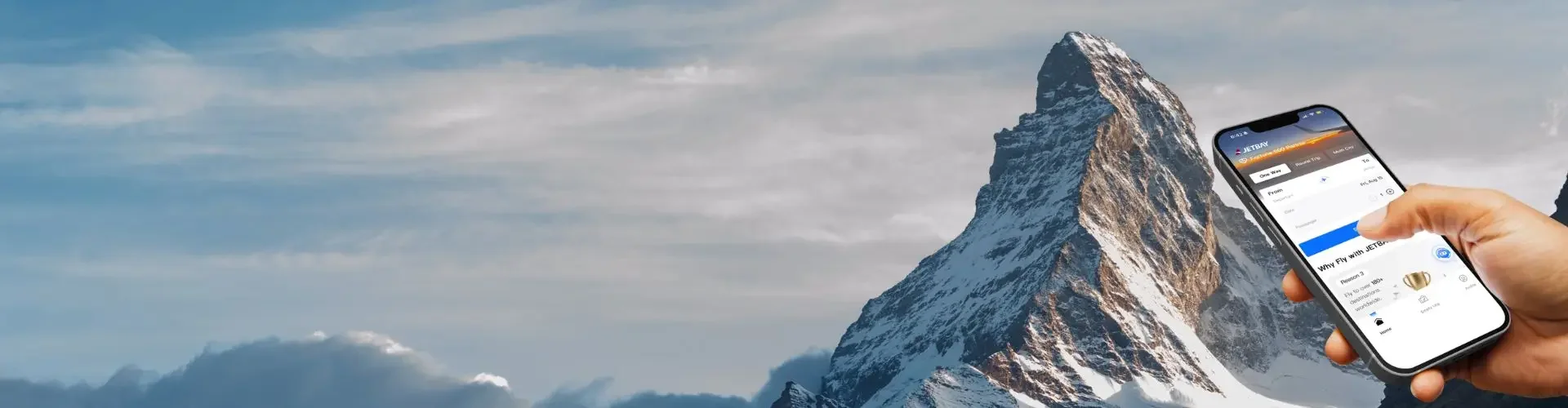 Hand holding smartphone displaying private jet booking app interface against snow-capped mountain backdrop