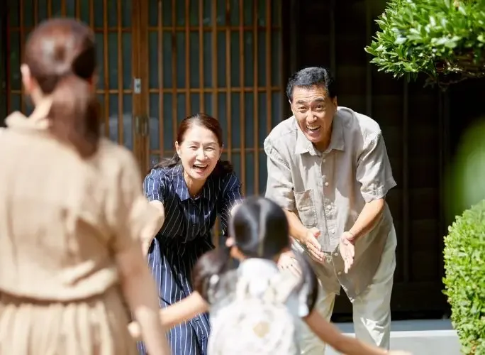 Happy Asian family greeting relatives at traditional home entrance during Lunar New Year celebration