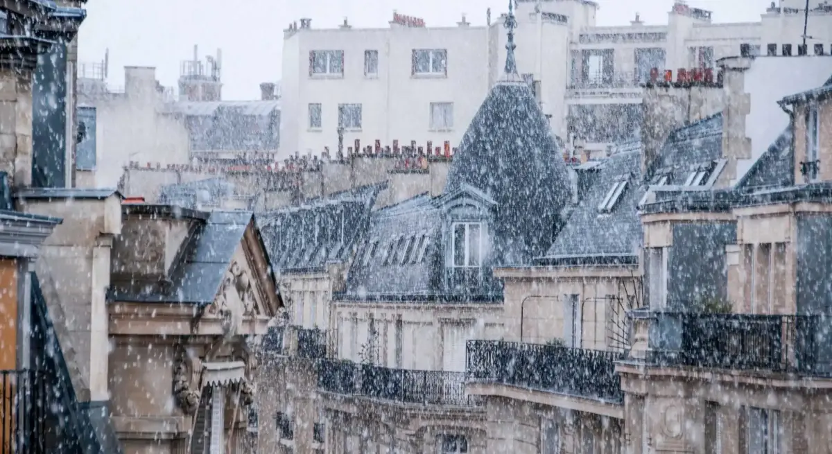Heavy snowfall blankets Parisian rooftops and balconies, showcasing winter charm for luxury travel destinations