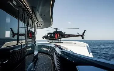 Helicopter approaching luxury yacht deck over Mediterranean waters for Monaco Grand Prix charter service