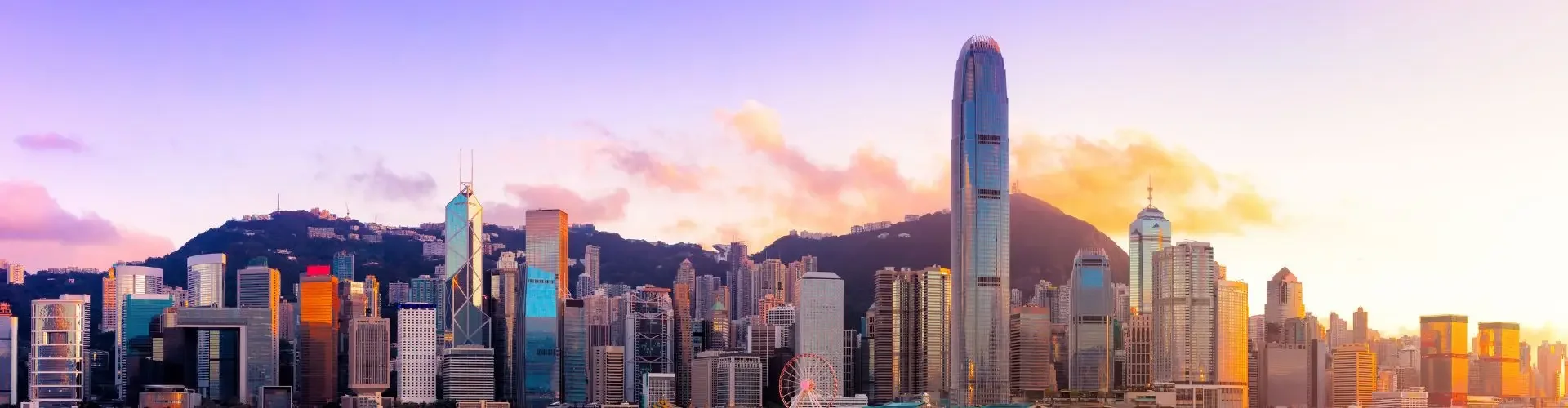 Hong Kong skyline at sunset with gleaming skyscrapers reflecting golden light across Victoria Harbour
