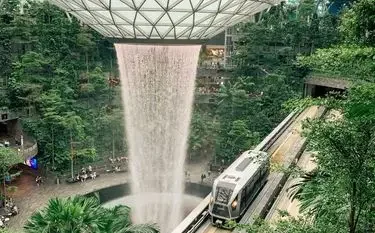 Can Private Jets Land at Changi Airport? Indoor waterfall cascades through geometric ceiling as train passes through Singapore Changi Airport terminal