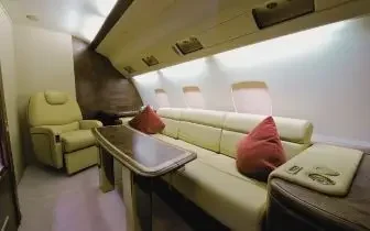 Luxurious private jet cabin interior with cream leather seating and polished wood table in Canada