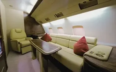 Luxurious private jet cabin interior featuring cream leather seating, polished wood table, and panoramic windows