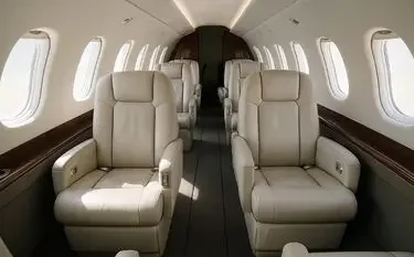 Luxurious private jet cabin interior featuring cream leather seats and panoramic windows for UK charter flights