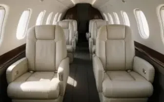 Luxurious private jet cabin interior with cream leather seats and polished wood accents for UK flights
