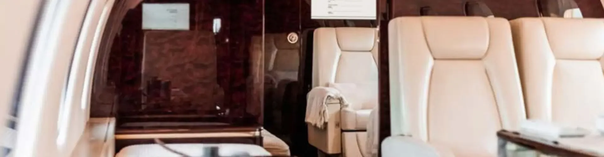 Canada Private Jet vs. First Class: Which One is Better? Luxurious private jet cabin interior with cream leather seats and polished wood finishes for premium travel