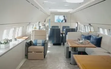 Luxurious private jet cabin interior with plush seating, polished wood tables, and panoramic windows