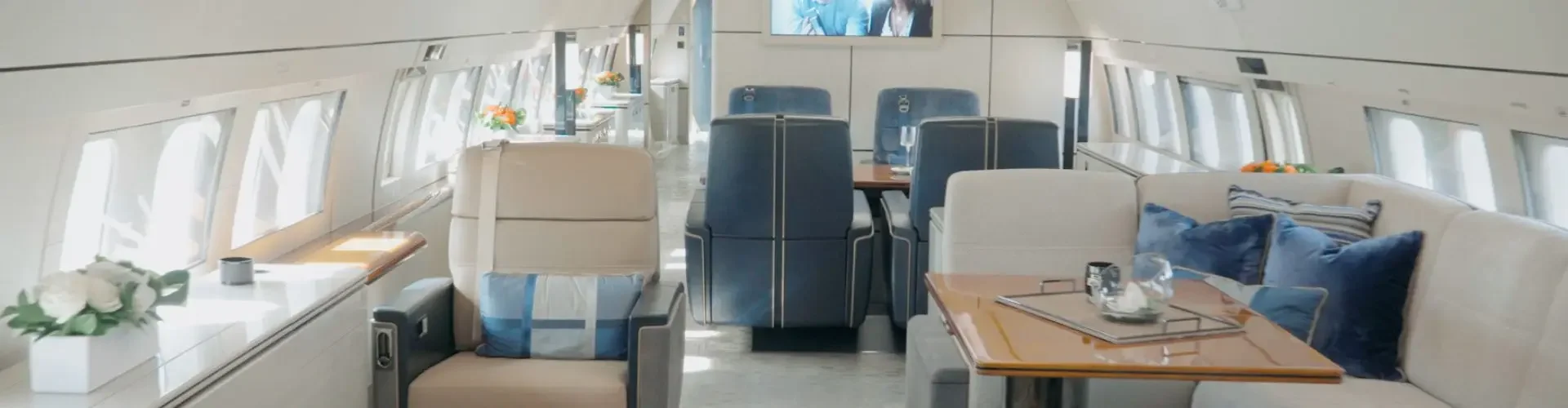 Luxurious private jet cabin interior with plush seating, polished wood tables, and panoramic windows