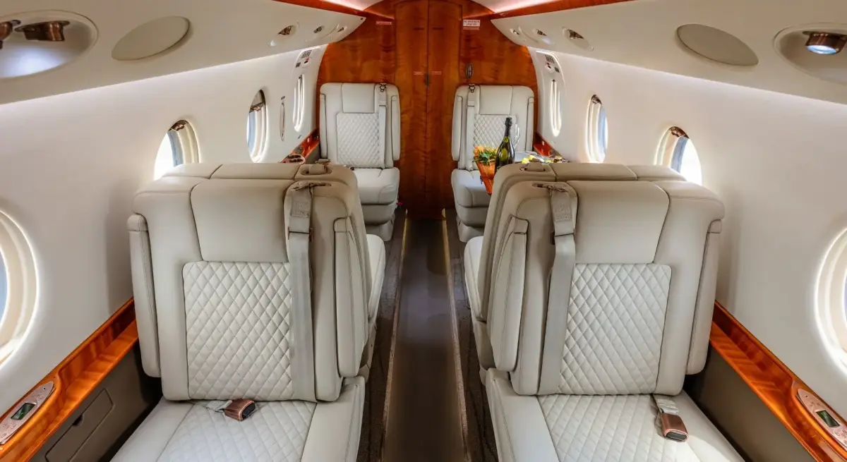 Luxurious private jet cabin interior featuring quilted leather seats and polished wood accents for premium travel