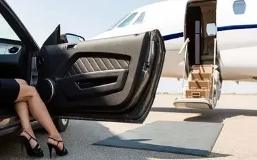 Luxury car door open beside private jet with passenger stepping out onto tarmac at exclusive airport