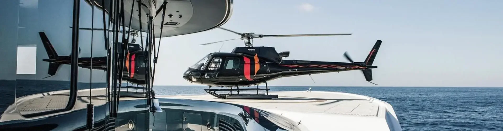 Helicopter approaching luxury yacht deck over Mediterranean waters for Monaco Grand Prix charter service