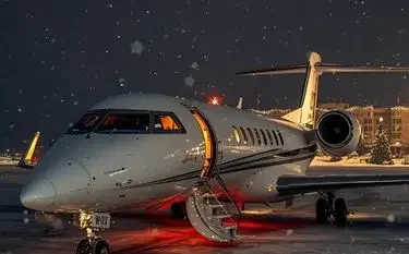 Luxury private jet illuminated on snowy tarmac at night, ready for last-minute holiday travel departure
