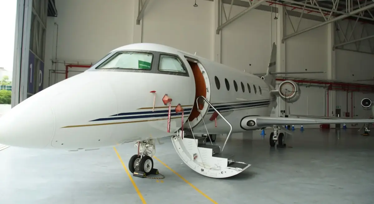 Luxury private jet with open cabin door in pristine hangar, ready for exclusive charter flights to St Moritz