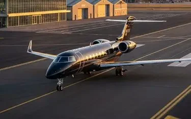 Can a Private Jet Land at Any UK Airport? (FAB, BQH, LTN explained) Luxury private jet positioned on airport tarmac at golden hour with modern hangars in background
