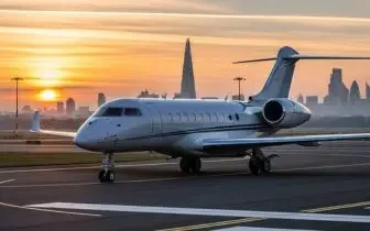 Luxury private jet positioned on airport tarmac at sunset with London skyline visible in background