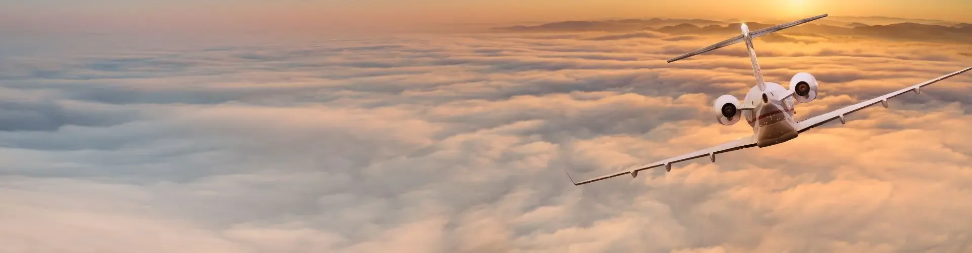 How Far Can a Private Jet Fly without Refueling? Private jet soaring above golden clouds at sunset showcasing long-distance flight capabilities