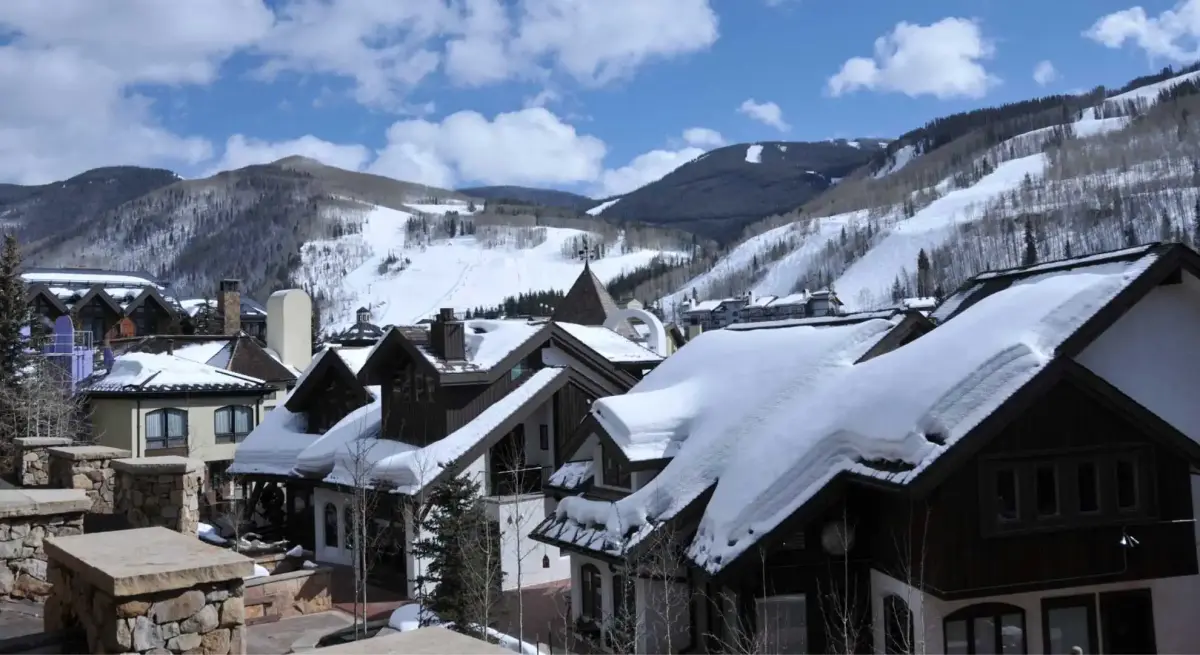 Luxury ski resort village with snow-covered chalets nestled beneath pristine mountain slopes and ski runs