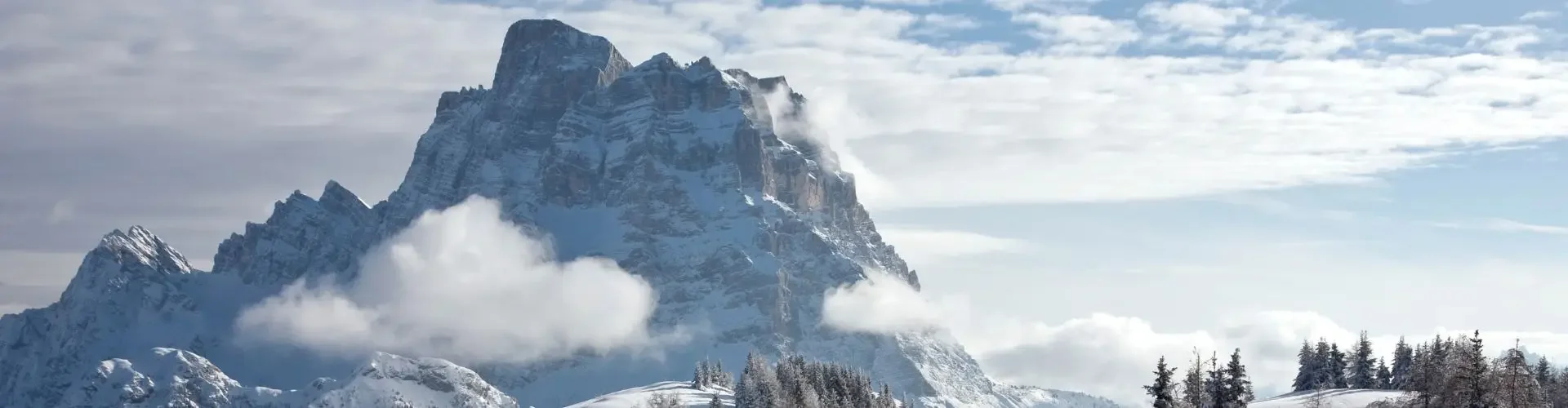 Top Ski Resorts to Visit by Private Jet This Winter Skier descending pristine Alpine slopes with dramatic snow-capped mountain peaks and evergreen forests