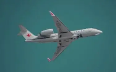 Medical air ambulance aircraft with red cross markings flying over turquoise waters in Canada