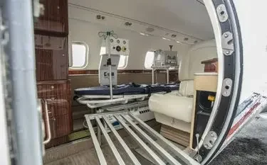 US Air Ambulance Cost & Insurance Considerations Medical equipment and stretcher inside luxury air ambulance cabin with wood paneling and leather seating