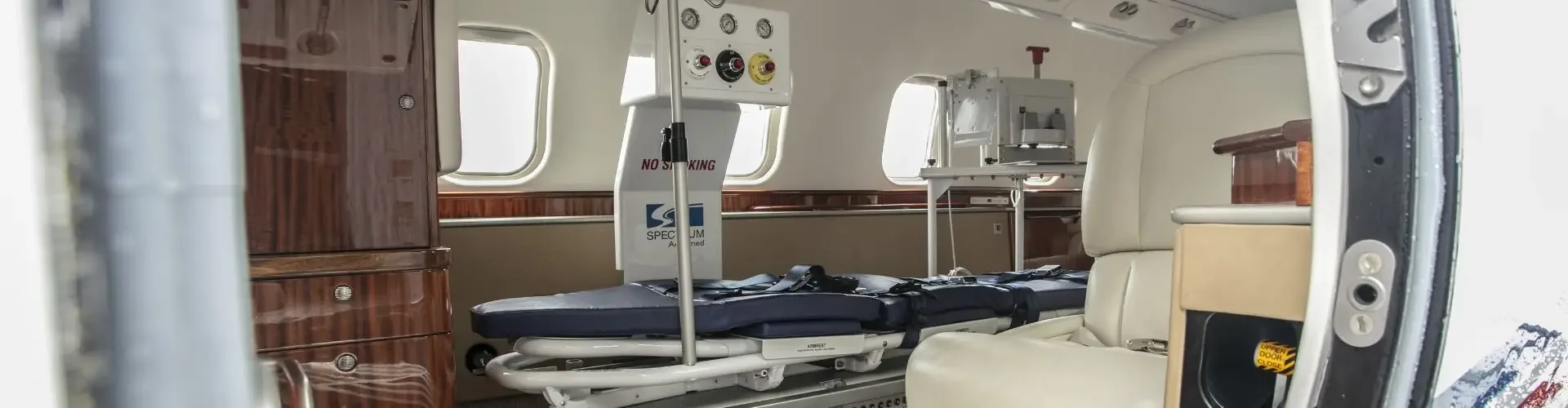 US Air Ambulance Cost & Insurance Considerations Medical equipment and stretcher inside luxury air ambulance cabin with wood paneling and leather seating
