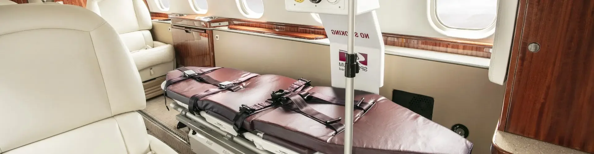Air Ambulance vs Commercial Medical Escort in the UK Medical stretcher equipped with monitoring devices inside luxury private jet cabin for air ambulance services