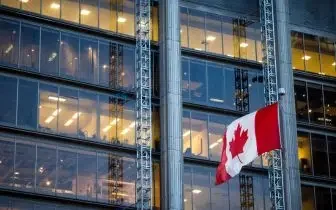 Modern Canadian office building with illuminated windows and red maple leaf flag representing business aviation costs