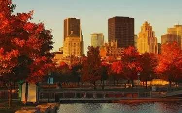 Private Jet Charter from Montréal–Trudeau International Airport Montreal skyline with autumn foliage framing downtown buildings during golden hour sunset