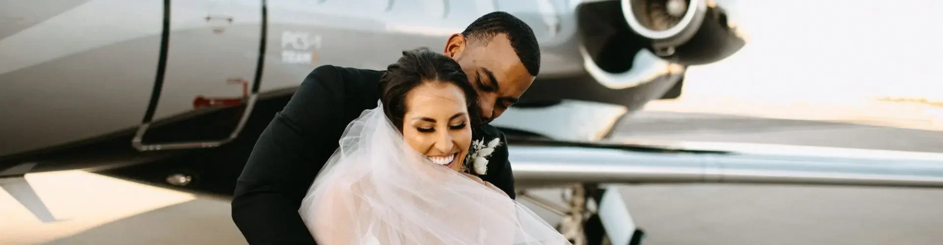 Private Jet Charter Flights for Destination Weddings: Personalisation Takes Flight Newlywed couple embracing beside luxury private jet on wedding day, showcasing romantic charter flight experience