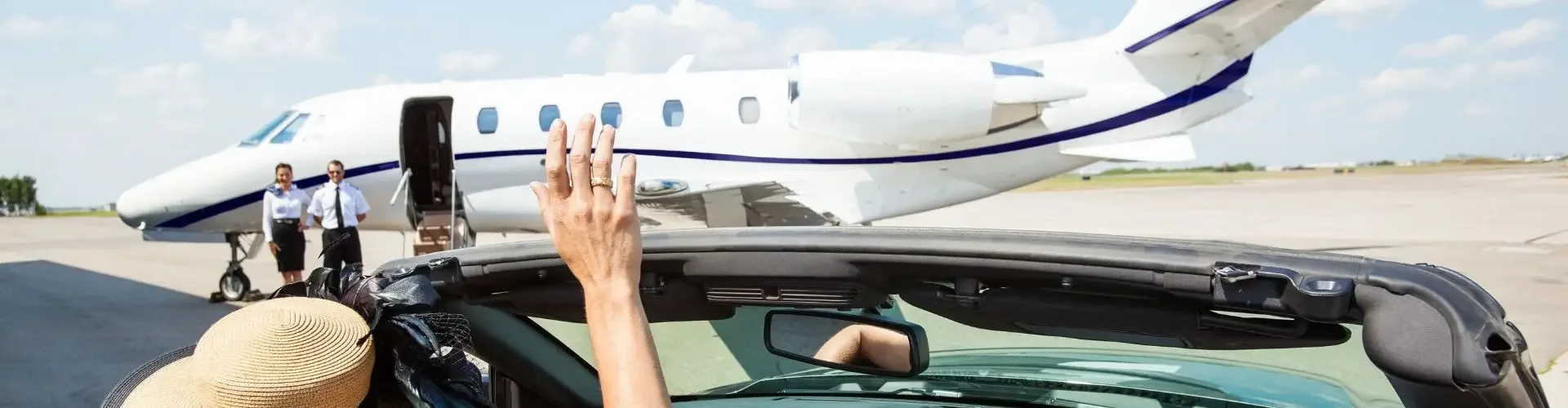 Common Jet Charter Misconceptions: What Private Flyers Should Really Expect Woman in convertible waving at luxury private jet on tarmac, illustrating accessible jet charter travel