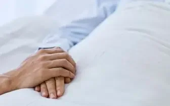 Patient hands resting on white hospital bedding highlighting need for emergency medical transport services
