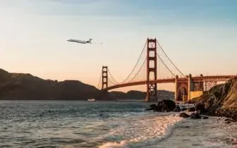 Private jet flying over Golden Gate Bridge at sunset, showcasing luxury business travel to San Francisco