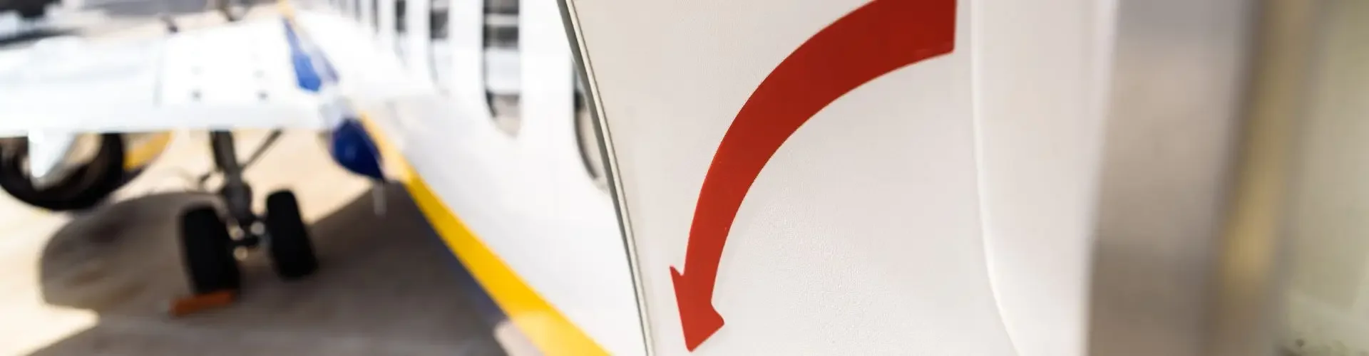 Aircraft door with red emergency handle open at airport, ready for urgent medical charter flight departure