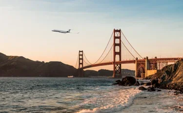 Private jet soaring over Golden Gate Bridge at sunset with San Francisco Bay waters below