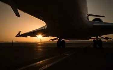 Private Jet vs Commercial Airlines: Which One is Right for You? Private jet silhouetted against golden sunset on tarmac, showcasing luxury travel advantages over commercial flights