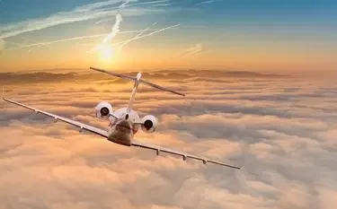 How Far Can a Private Jet Fly without Refueling? Private jet soaring above golden clouds at sunset showcasing long-distance flight capabilities