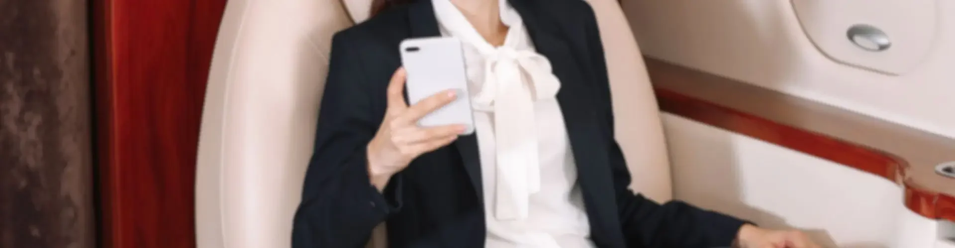 Professional businesswoman relaxing in luxury private jet cabin while using smartphone during flight