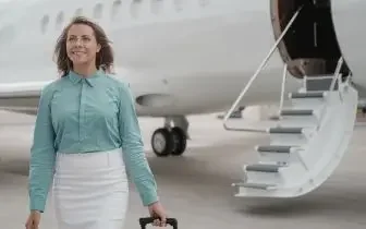 Professional woman walking confidently toward private jet stairs, representing luxury travel in Canada