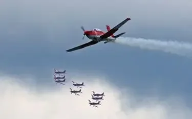 Red aerobatic aircraft leading formation five planes white smoke cloudy sky for private jet charter passengers