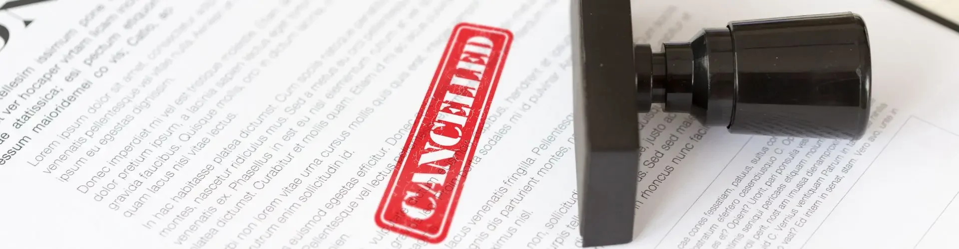 Red cancelled stamp on contract document with rubber stamp beside it on wooden desk surface