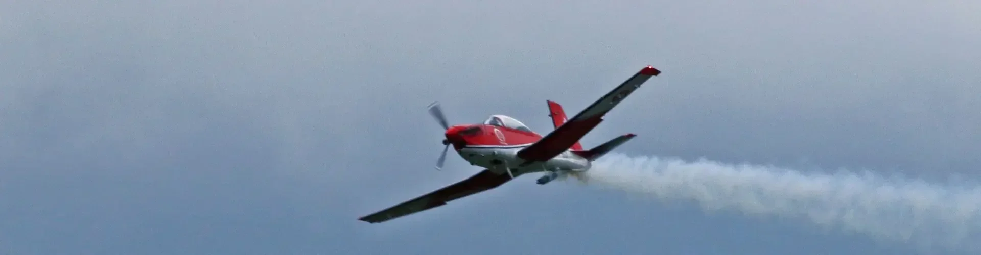 Red aerobatic aircraft leading formation five planes white smoke cloudy sky for private jet charter passengers