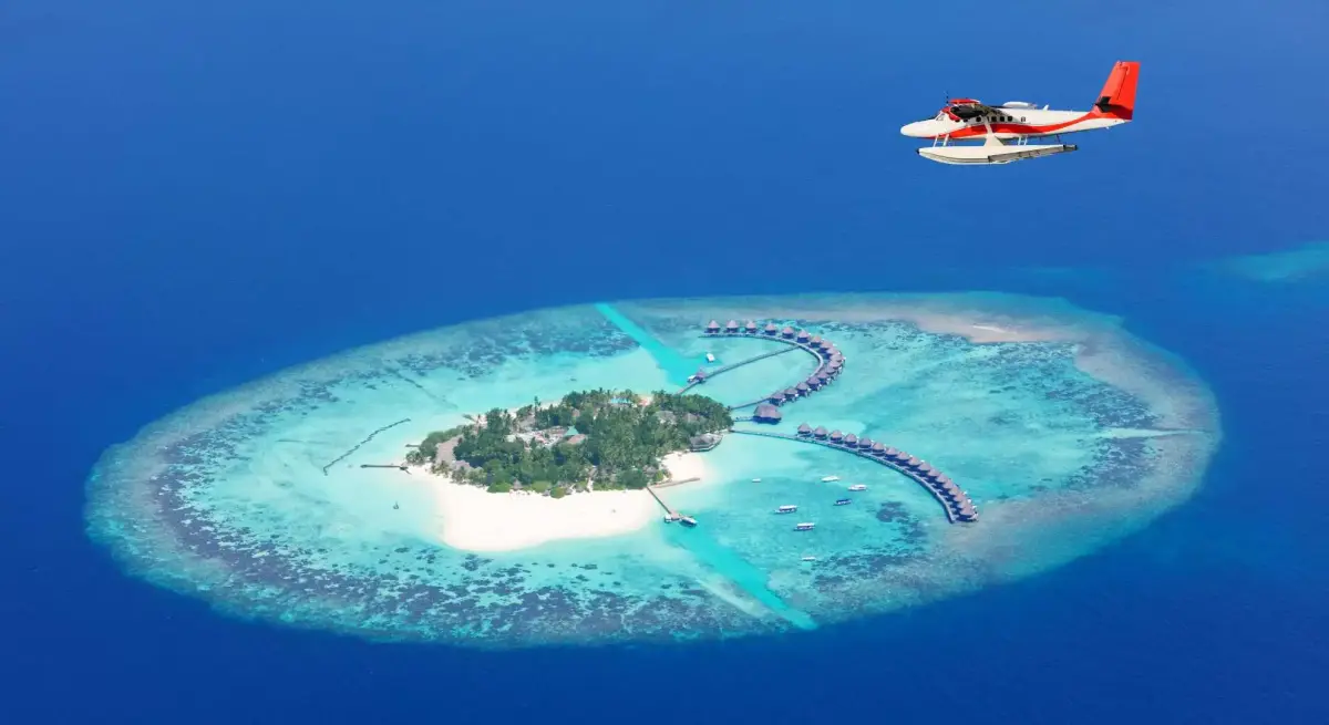 Seaplane approaching luxury Maldives resort island with overwater villas, showcasing exclusive winter escape destinations