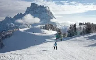 Skier descending pristine Alpine slopes with dramatic mountain peaks, perfect for luxury Christmas ski holidays
