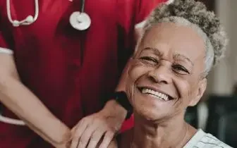 Smiling elderly patient receiving compassionate care from medical professional in healthcare setting