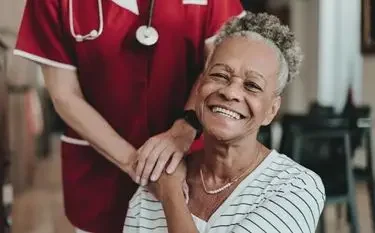 Smiling elderly patient receiving compassionate care from medical professional in comfortable healthcare setting