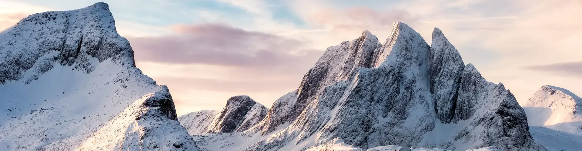 2026 Winter Olympics Private Jet Charter Guide Snow-covered Alpine peaks bathed in golden sunset light, showcasing the dramatic mountain terrain of the 2026 Winter Olympics venue