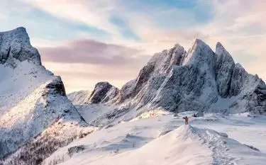 2026 Winter Olympics Private Jet Charter Guide Snow-covered Alpine peaks bathed in golden sunset light, showcasing the dramatic mountain terrain of the 2026 Winter Olympics venue