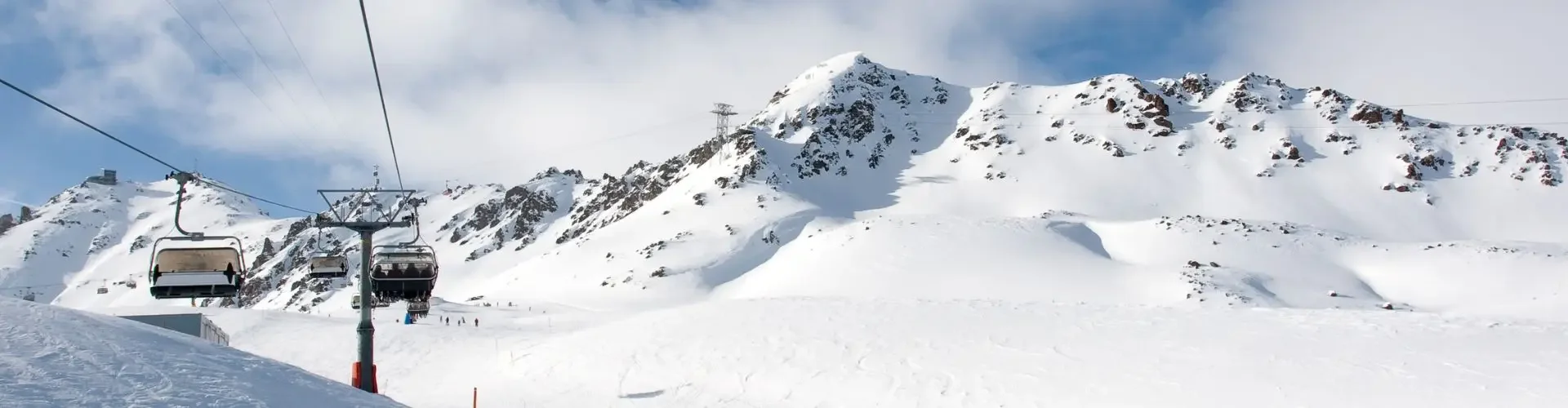 Cable car ascending snow-covered Alpine slopes with dramatic mountain peaks in St. Moritz ski resort